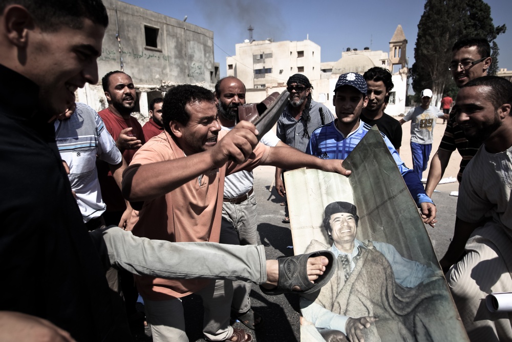 Ливийцы «порочат» портрет Каддафи после падения Триполи в руки повстанцев. 2011 г.