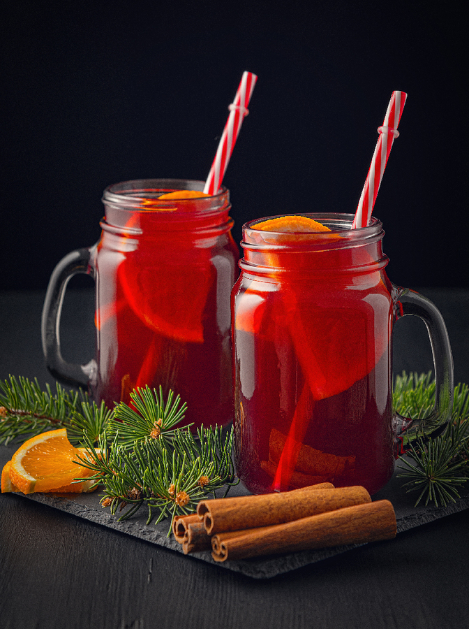 Christmas mulled red wine with spices and fruits on a wooden black rustic table. Traditional hot drink at Christmas time